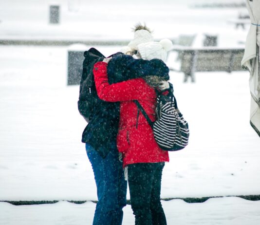 오늘은 어떤 뜻 깊은 일을 해볼까? person in red and black jacket and black pants carrying white dog on snow covered ground
