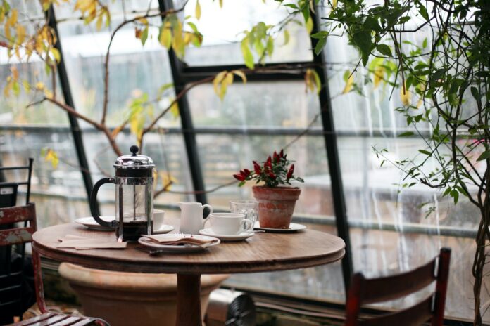 round brown wooden table with french press on top with white ceramic teacup beside