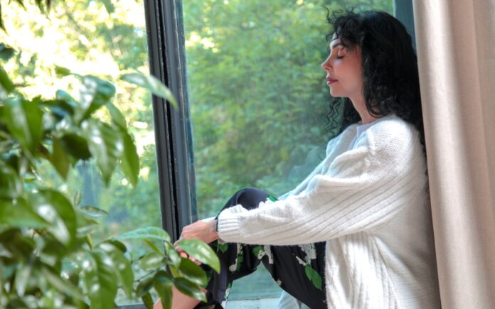a woman sitting on a window sill looking out the window