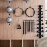 “필라테스, 일상에 녹여 더 건강하게…한국인 맞춤 실천법 인기” Gym equipment neatly organized on a wooden wall